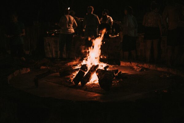 wood burning in a late night campfire people in the background